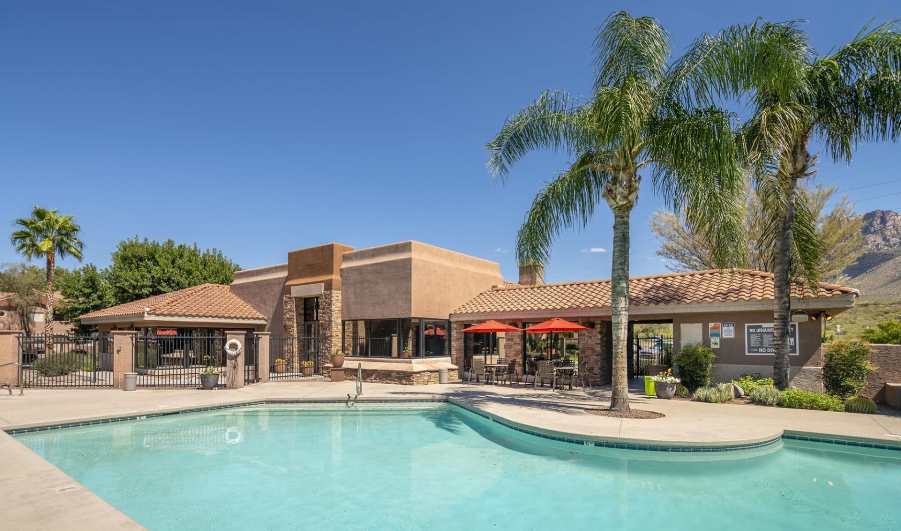 Shimmering resort-style pool a swimming pool in front of a house with palm trees
